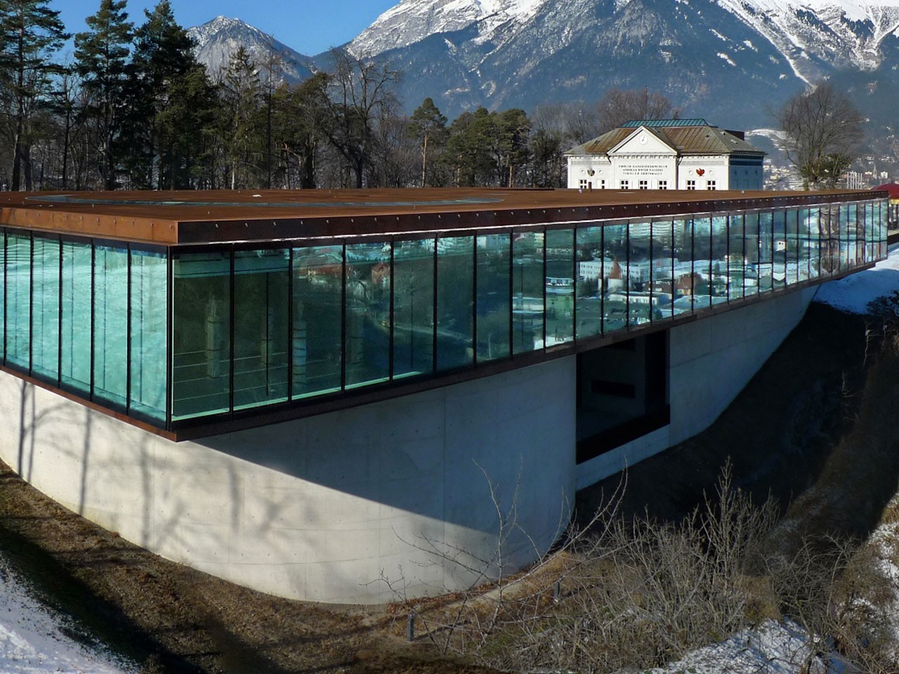 Türkisfarbener Fassadenbau aus Glas vor Berghintergrund in Tirol